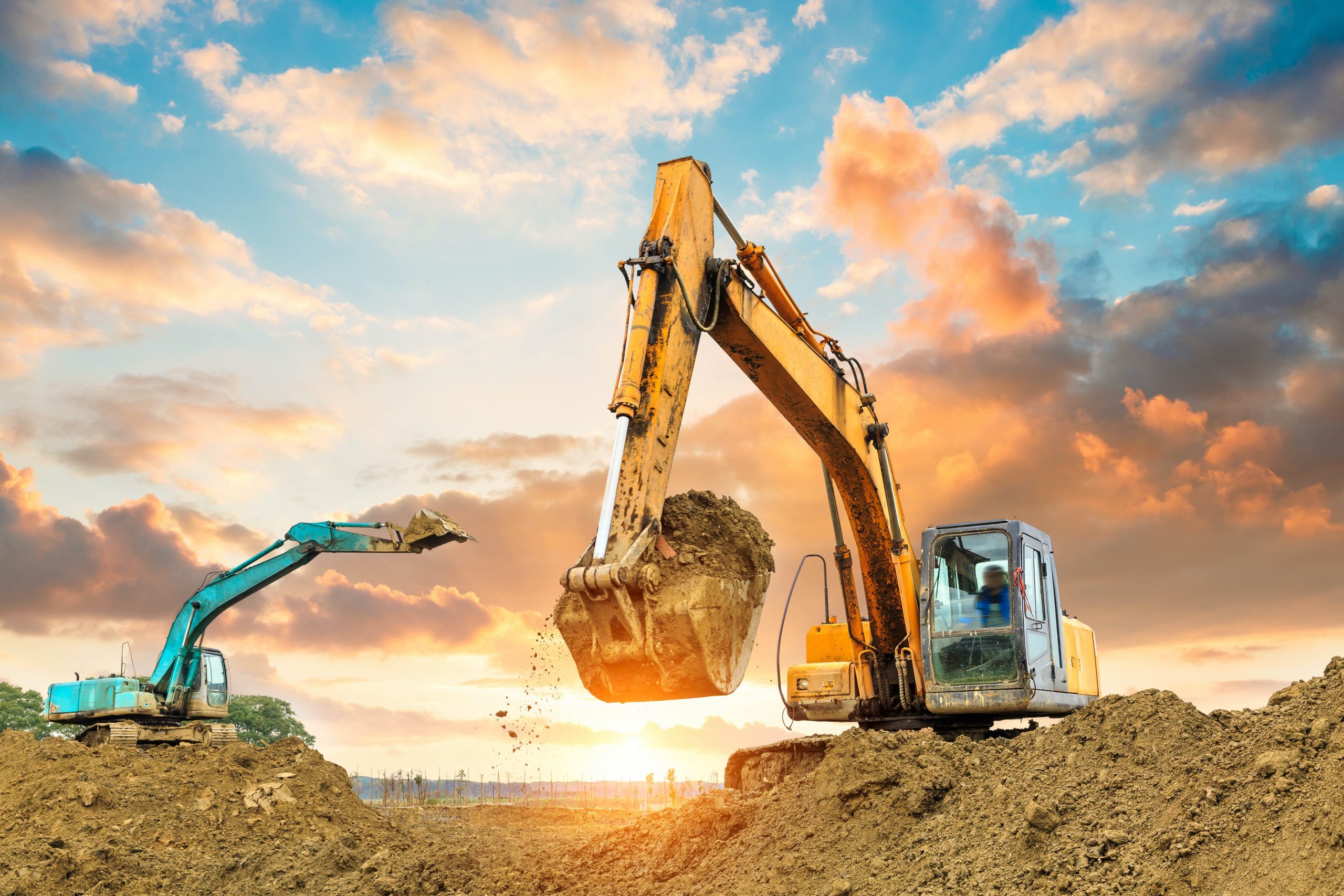 Excavators working on a construction site at sunset